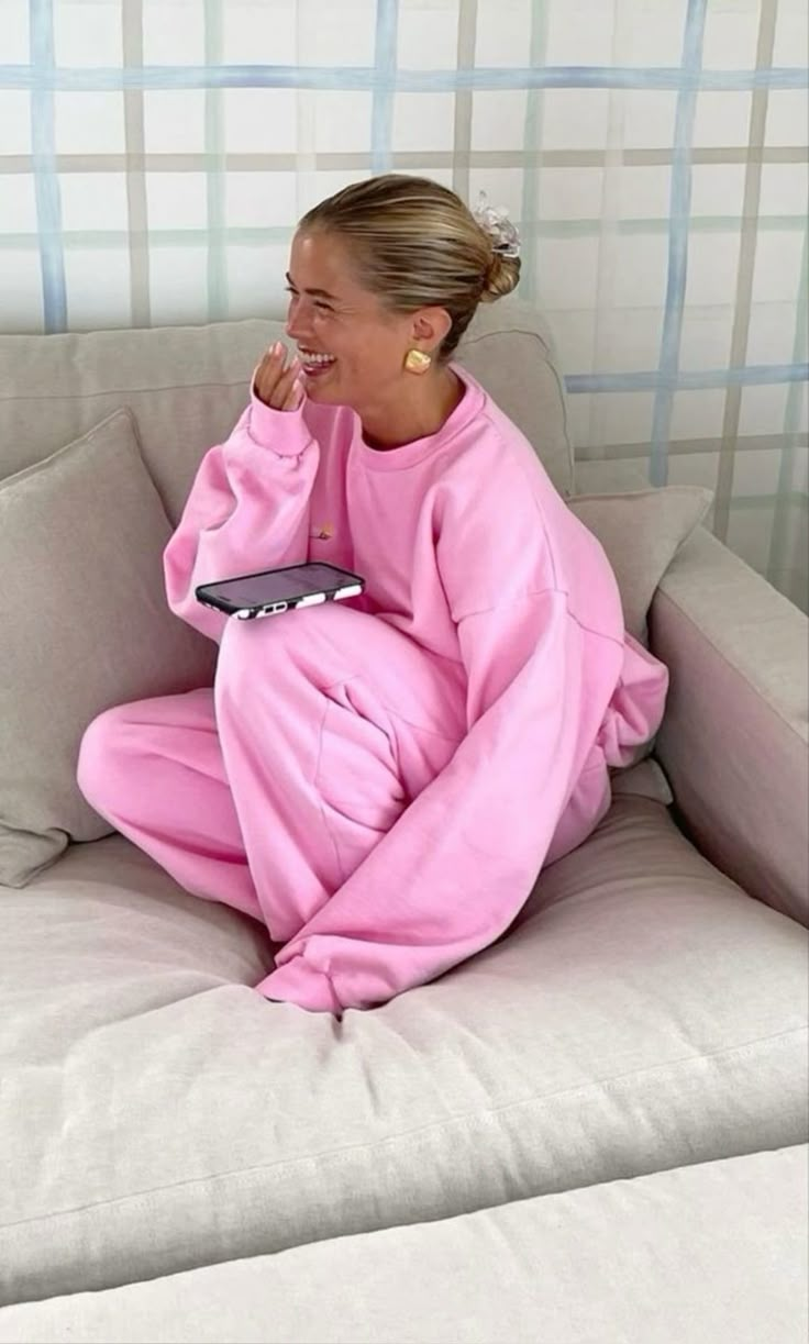 Pinterest inspiration: a woman laughing in a pink sweatsuit on a sofa