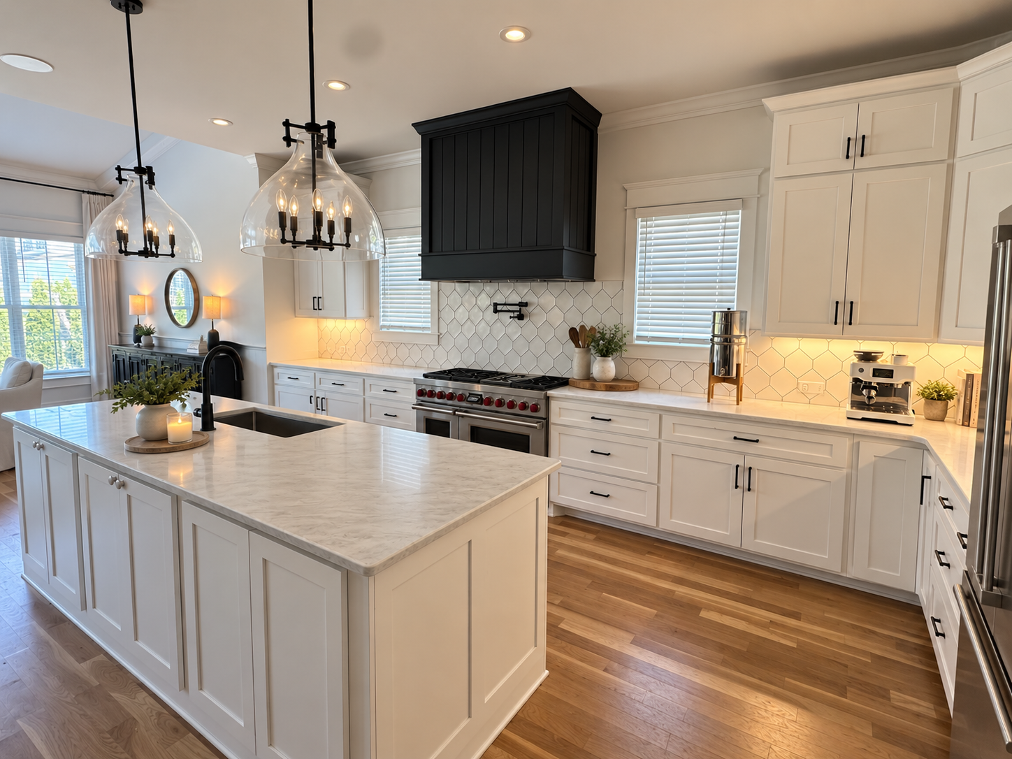 Katie's actual kitchen: white cabinets, large marble island, black range hood and glass pendant lights