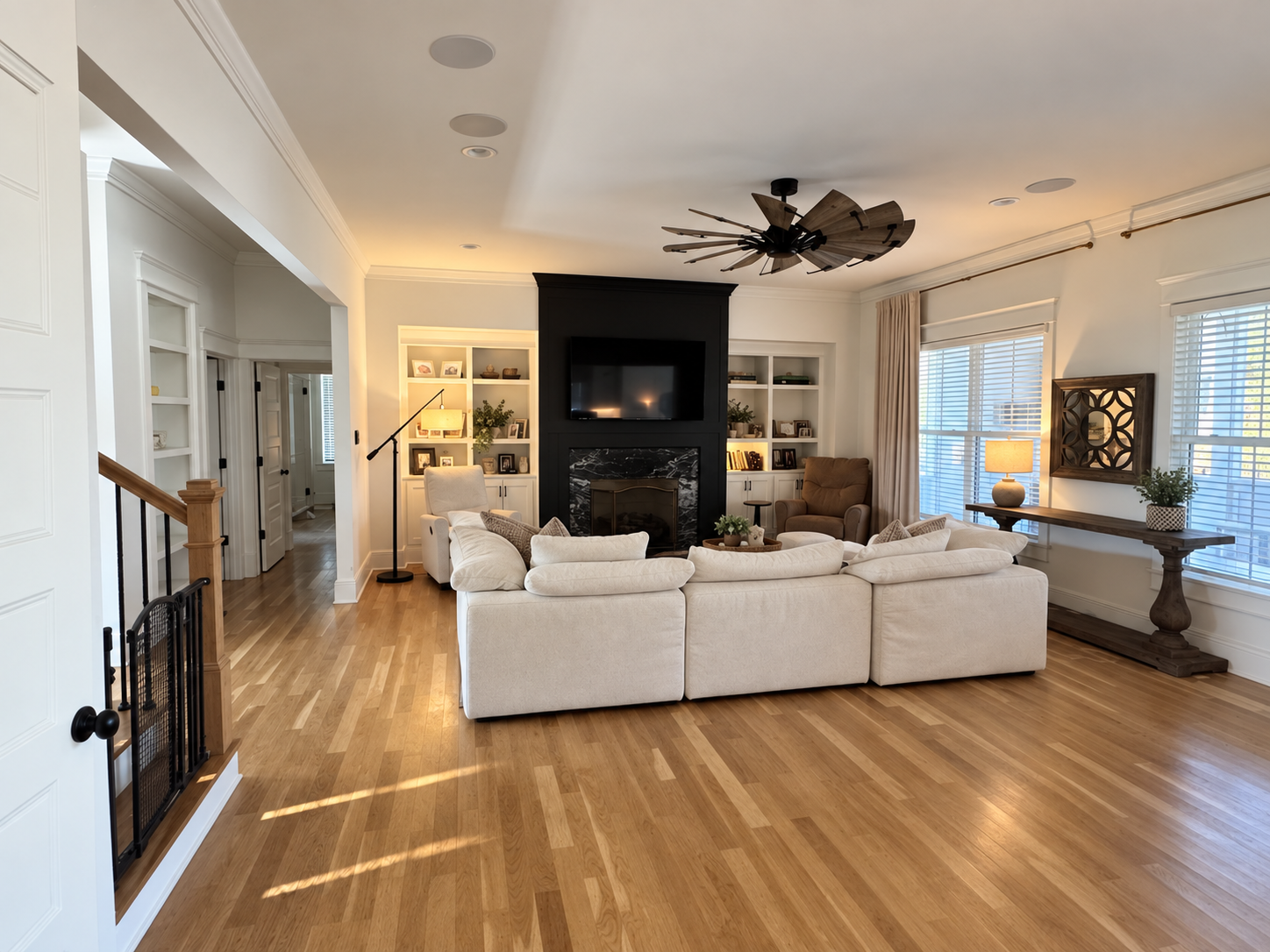 Katie's actual living room: white sectional, black fireplace wall with built-in shelves and hardwood floors